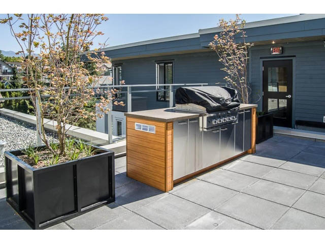Furnished patio with modern grill and wooden accents, city view in background. - 501 - 221 East 3rd Street, North Vancouver