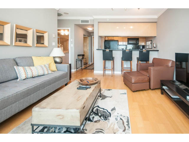Bright living room with hardwood floors, modern furniture, and a kitchen counter in the background. - 3602 - 1111 W Pender, Vancouver Downtown