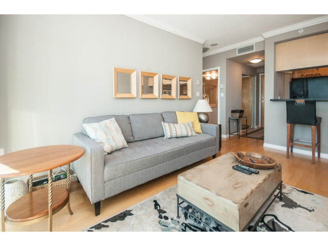 Furnished living room with gray sectional, wooden coffee table, and city view. - 3602 - 1111 W Pender, Vancouver Downtown