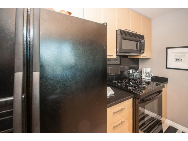 Bright kitchen with black countertops and stainless steel appliances, modern design. - 3602 - 1111 W Pender, Vancouver Downtown