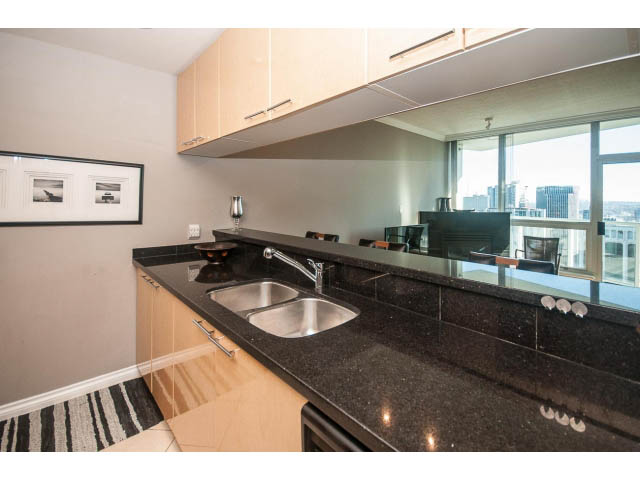 Bright kitchen with black granite countertops, city view, and modern cabinetry. - 3602 - 1111 W Pender, Vancouver Downtown