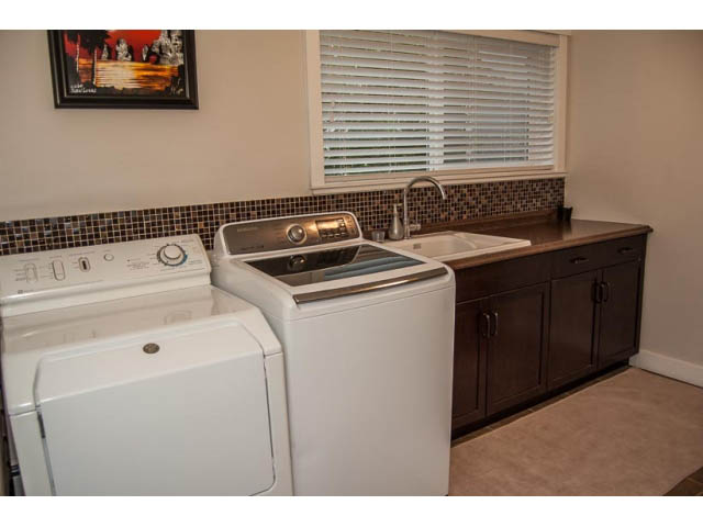 Shared laundry room with dark cabinets, white appliances, and a window with blinds. - 2269 East 40th Ave, Vancouver East Side