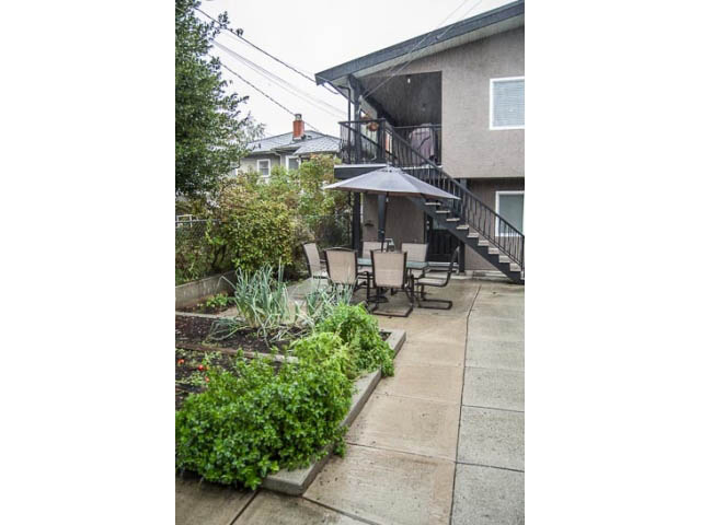Shared patio with outdoor furniture and umbrella, leading to a staircase. - 2269 East 40th Ave, Vancouver East Side