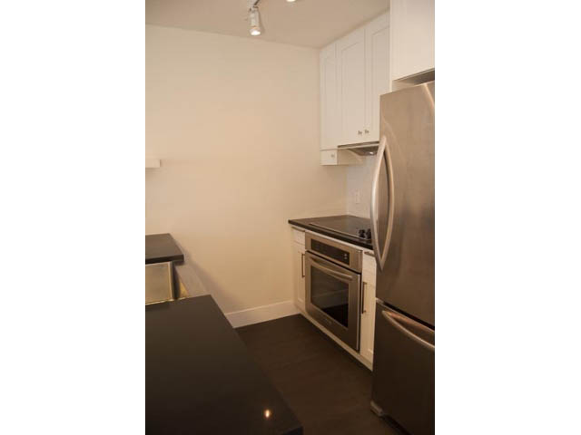 Bright kitchen with stainless steel appliances and dark countertops. - 2306 - 888 Homer Street, Vancouver Downtown
