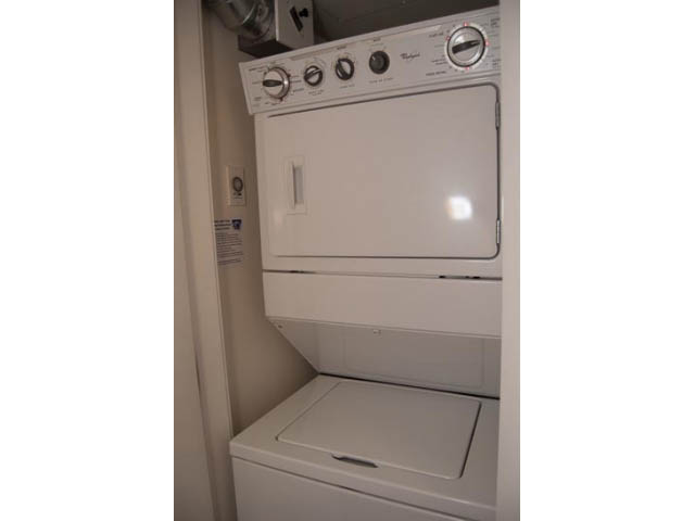 Bright laundry room with stacked washer and dryer, clean white surfaces. - 2306 - 888 Homer Street, Vancouver Downtown