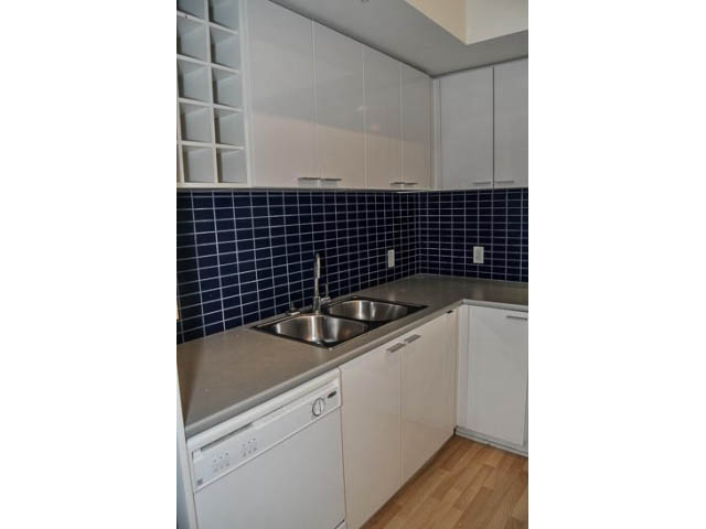 Bright kitchen with stainless steel countertops, hardwood floors, and a blue tiled backsplash. - 138 Dunsmuir Street, Vancouver Downtown