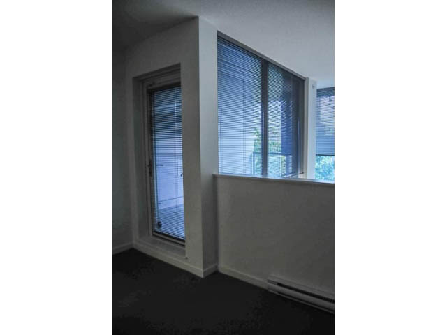Bright living room with large windows and blinds, showcasing a city view. - 138 Dunsmuir Street, Vancouver Downtown
