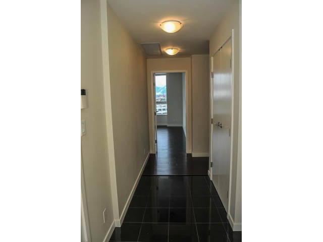 Bright hallway leading to a city view, featuring black tiled flooring and white walls. - 900 - 9 Smithe Mews, Vancouver Downtown