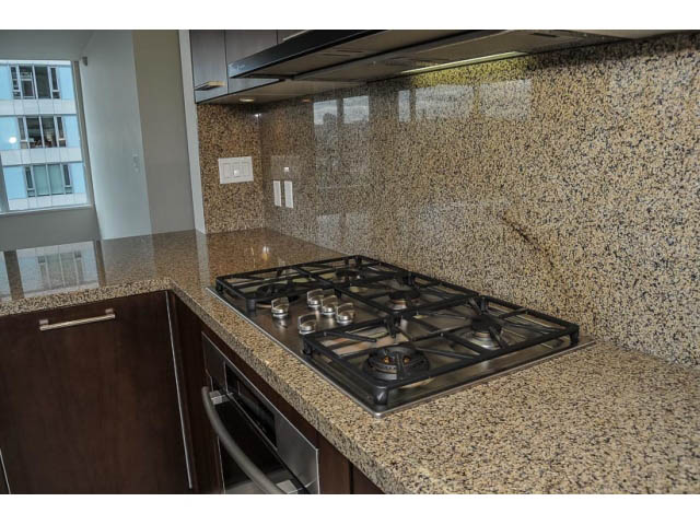 Bright kitchen with granite countertops and modern gas stove, city view through large windows. - 900 - 9 Smithe Mews, Vancouver Downtown