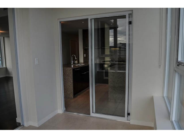 Bright kitchen with granite countertops and sliding glass doors leading to a patio, offering a city view. - 900 - 9 Smithe Mews, Vancouver Downtown