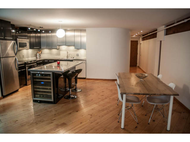 Bright kitchen with stainless steel appliances, hardwood floors, and a dining area with modern chairs. - 5-4 - 550 Beatty Street, Vancouver Downtown