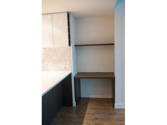 Bright kitchen with white cabinets, dark countertops, and hardwood floors. - 906 - 110 Switchmen St, Vancouver East Side