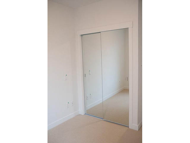 Bright bedroom with sliding mirrored closet doors and beige carpet. - 906 - 110 Switchmen St, Vancouver East Side