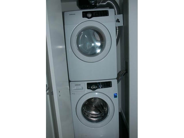 Bright laundry room with stacked washer and dryer, clean white surfaces. - 906 - 110 Switchmen St, Vancouver East Side