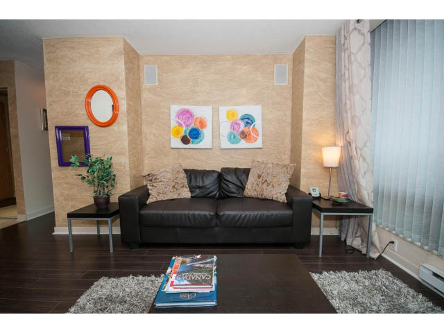 Furnished living room with modern decor, black leather couch, abstract art, and hardwood floors. - 507 - 1200 West Georgia Street, Vancouver Downtown