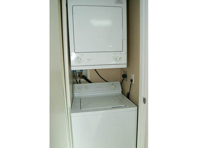 Bright laundry room with stacked washer and dryer, white cabinets. - 1406 - 1003 Burnaby Street, Vancouver Downtown