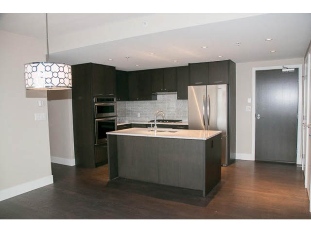 Furnished kitchen with dark wood cabinets, white countertops, and stainless steel appliances. - 407-150 West 15th Street, North Vancouver