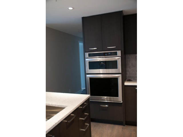 Bright kitchen with dark cabinetry, stainless steel appliances, and granite countertops. - 407-150 West 15th Street, North Vancouver
