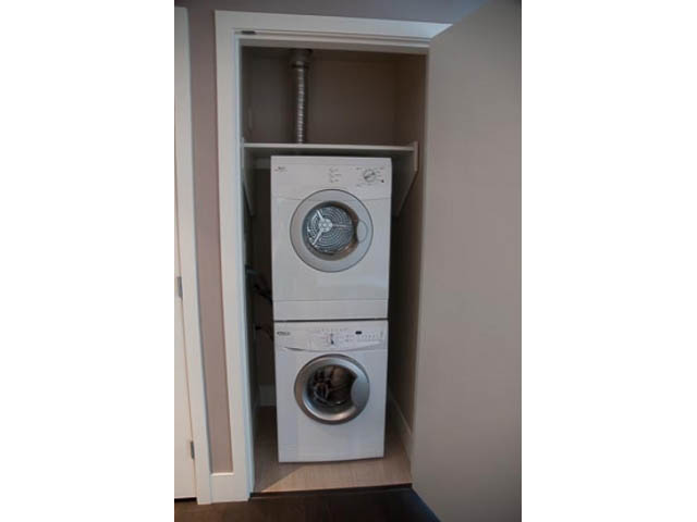 Laundry room with stacked washer and dryer, compact storage. - 407-150 West 15th Street, North Vancouver