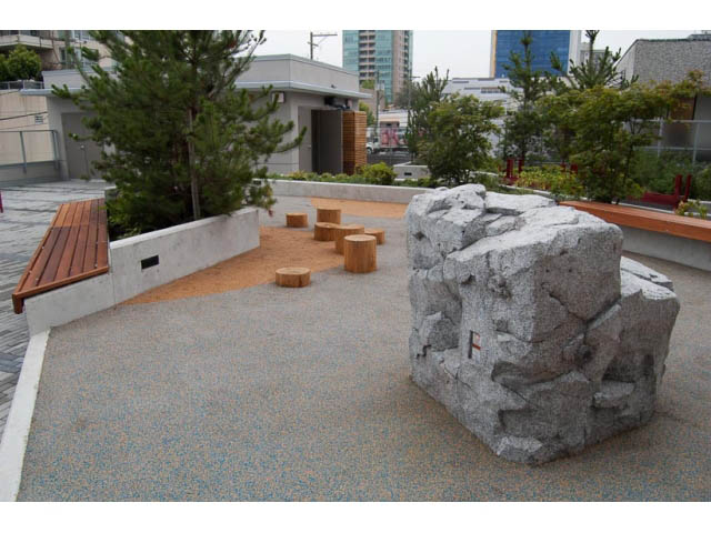 Furnished living room with large rock feature and wooden bench. - 407-150 West 15th Street, North Vancouver