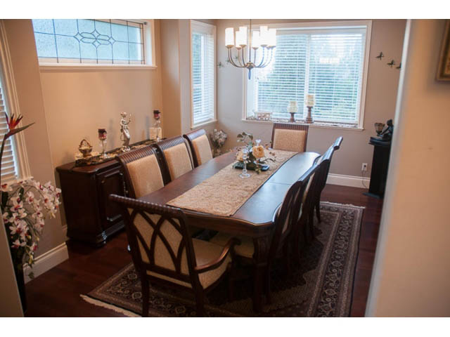 Furnished dining room with hardwood floors, large windows, and a chandelier. - 4287 Madeley Rd, North Vancouver