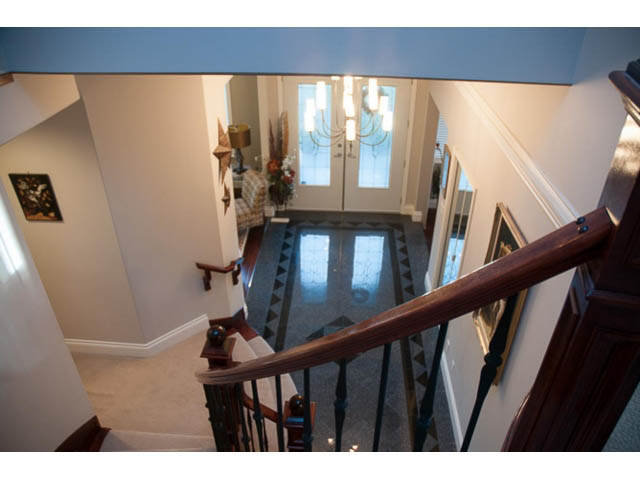 Staircase leading to a bright, open-concept living area with a chandelier and patterned rug. - 4287 Madeley Rd, North Vancouver