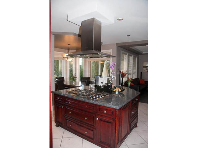 Bright kitchen with granite countertops, dark wood cabinets, and a large island. - 4287 Madeley Rd, North Vancouver