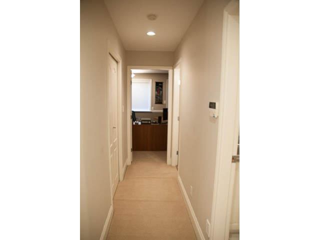 Furnished hallway with carpeted floors and white walls leading to a door. - 4287 Madeley Rd, North Vancouver