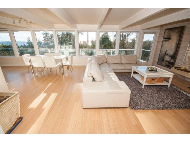 Bright living room with white sectional, hardwood floors, and city view. - 2720 Rosebery Avenue, West Vancouver