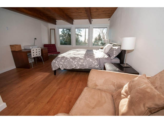 Bright bedroom with hardwood floors, large windows, and a cozy sofa. - 2720 Rosebery Avenue, West Vancouver