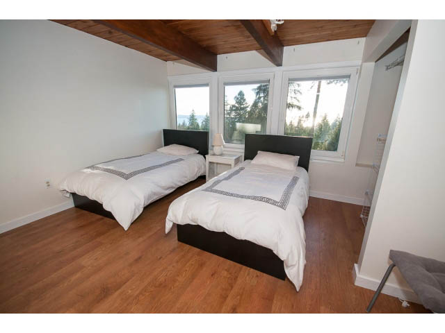 Spacious bedroom with hardwood floors, large windows, and a cozy bed setup. - 2720 Rosebery Avenue, West Vancouver