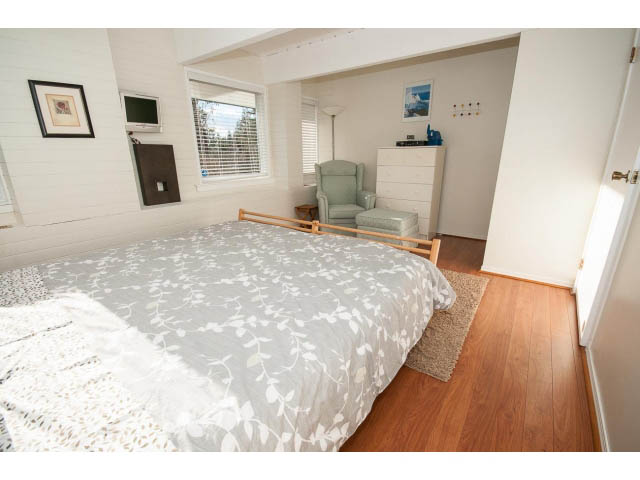 Spacious bedroom with hardwood floors and a cozy armchair. - 2720 Rosebery Avenue, West Vancouver
