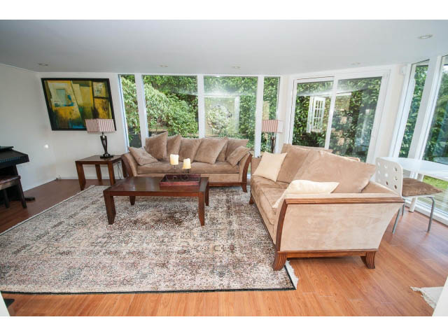 Spacious living room with large windows, hardwood floors, and a cozy sofa setup. - 2720 Rosebery Avenue, West Vancouver