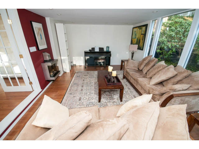 Bright living room with hardwood floors, large windows, and a cozy sofa setup. - 2720 Rosebery Avenue, West Vancouver