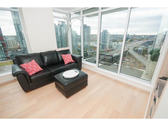 Bright living room with hardwood floors, city view, and black leather furniture. - 1707 - 1351 Continental St, Vancouver Downtown