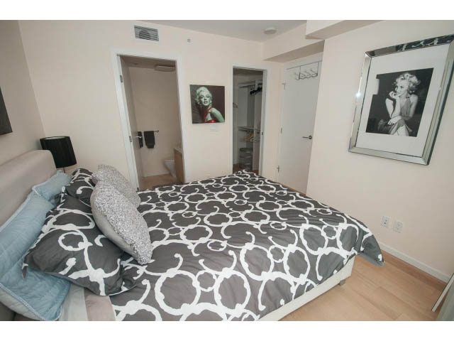 Bright bedroom with patterned bedding, light wood floors, and framed Marilyn Monroe art. - 1707 - 1351 Continental St, Vancouver Downtown