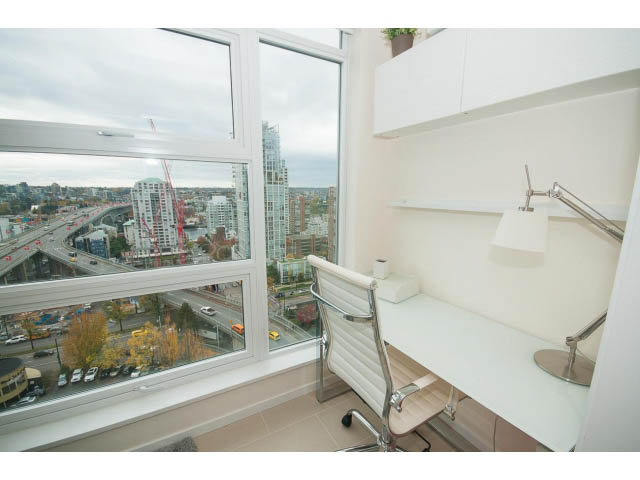 Bright and airy den with large windows offering a stunning city view, white walls, and modern furnishings.