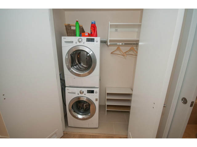 Laundry room with stacked washer and dryer, hangers, and cleaning supplies. - 1707 - 1351 Continental St, Vancouver Downtown