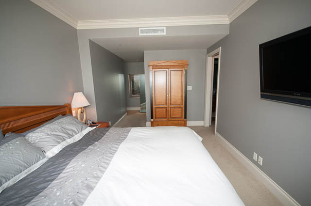 Spacious bedroom with neatly made bed, wooden closet, and mounted TV. - 2503 - 428 Beach Crescent, Vancouver Downtown
