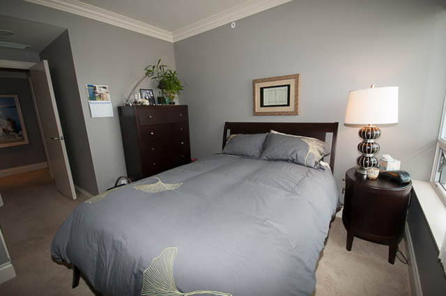 Furnished bedroom with gray bedding, wooden nightstand, and lamp. - 2503 - 428 Beach Crescent, Vancouver Downtown