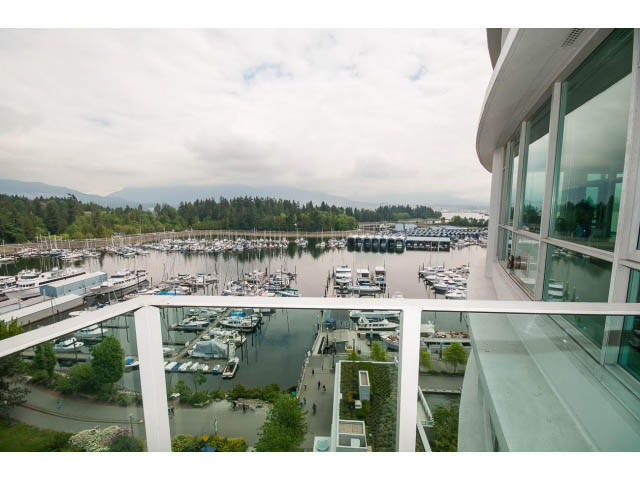 Bright balcony with stunning city view and marina, featuring modern glass railings and panoramic windows.