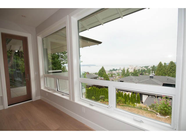 Bright living room with large windows, hardwood floors, and city view. - 905 Braeside St, West Vancouver
