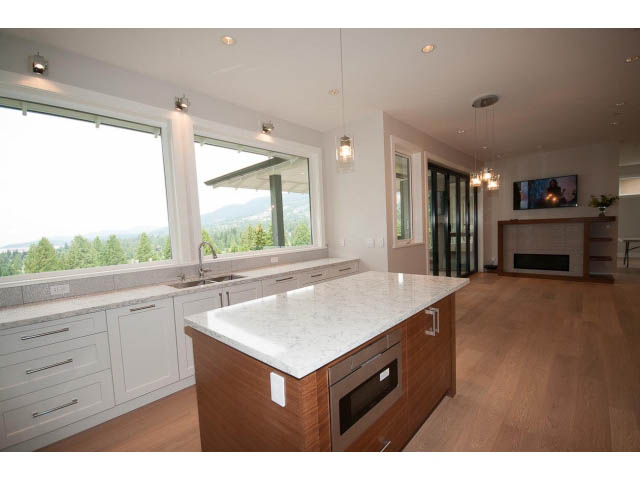 Bright kitchen with white cabinetry, granite countertops, hardwood floors, and a city view. - 905 Braeside St, West Vancouver