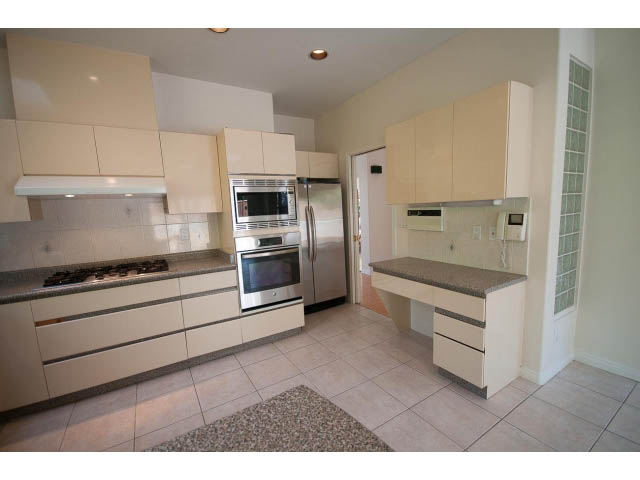 Bright kitchen with light beige cabinets, granite countertops, and stainless steel appliances. - 1559 Mathers Ave, West Vancouver