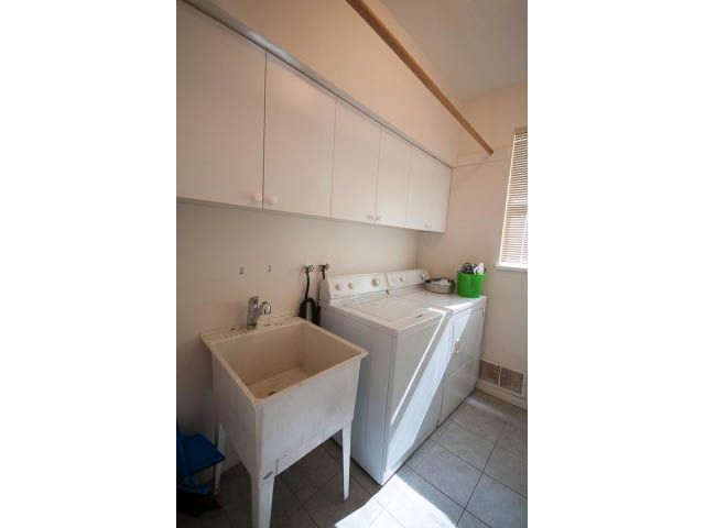 Bright laundry room with white cabinets and a utility sink. - 1559 Mathers Ave, West Vancouver