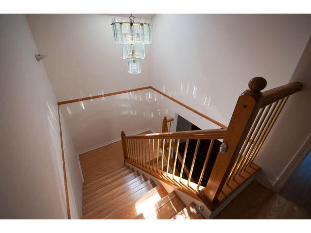 Staircase with wooden banisters and chandelier, leading to upper floors. - 1559 Mathers Ave, West Vancouver