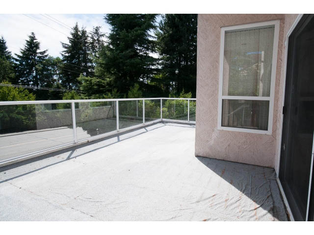 Furnished balcony with glass railing and view of trees. - 1559 Mathers Ave, West Vancouver