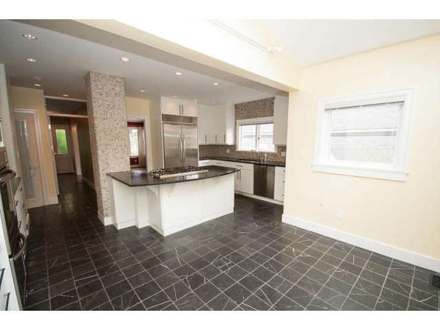 Bright kitchen with modern stainless steel appliances and dark marble countertops. - 3407 West 34th Ave, Vancouver West Side