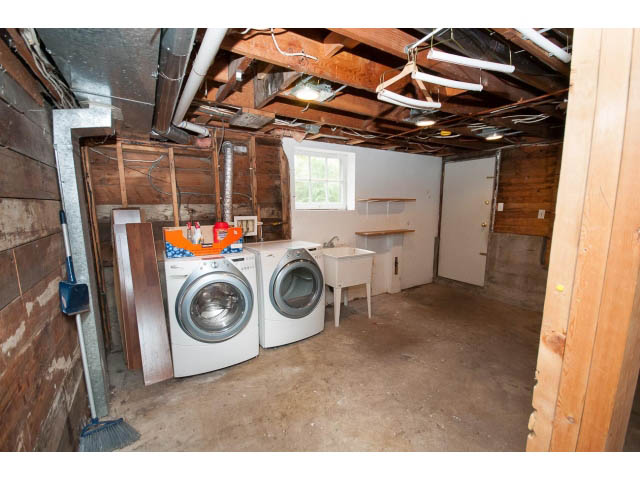 Shared laundry room with exposed ceiling and wooden beams, cluttered with appliances and tools. - 3407 West 34th Ave, Vancouver West Side