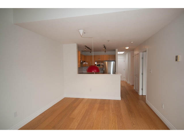 Open-concept living area with hardwood floors and modern kitchen cabinets. - 409 - 3023 West 4th Ave., Vancouver West Side